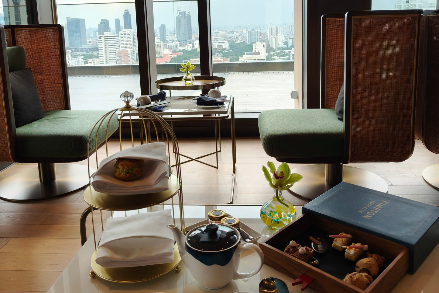 Modern afternoon tea set by window with Bangkok city view at Maa-Lai Library Kimpton hotel