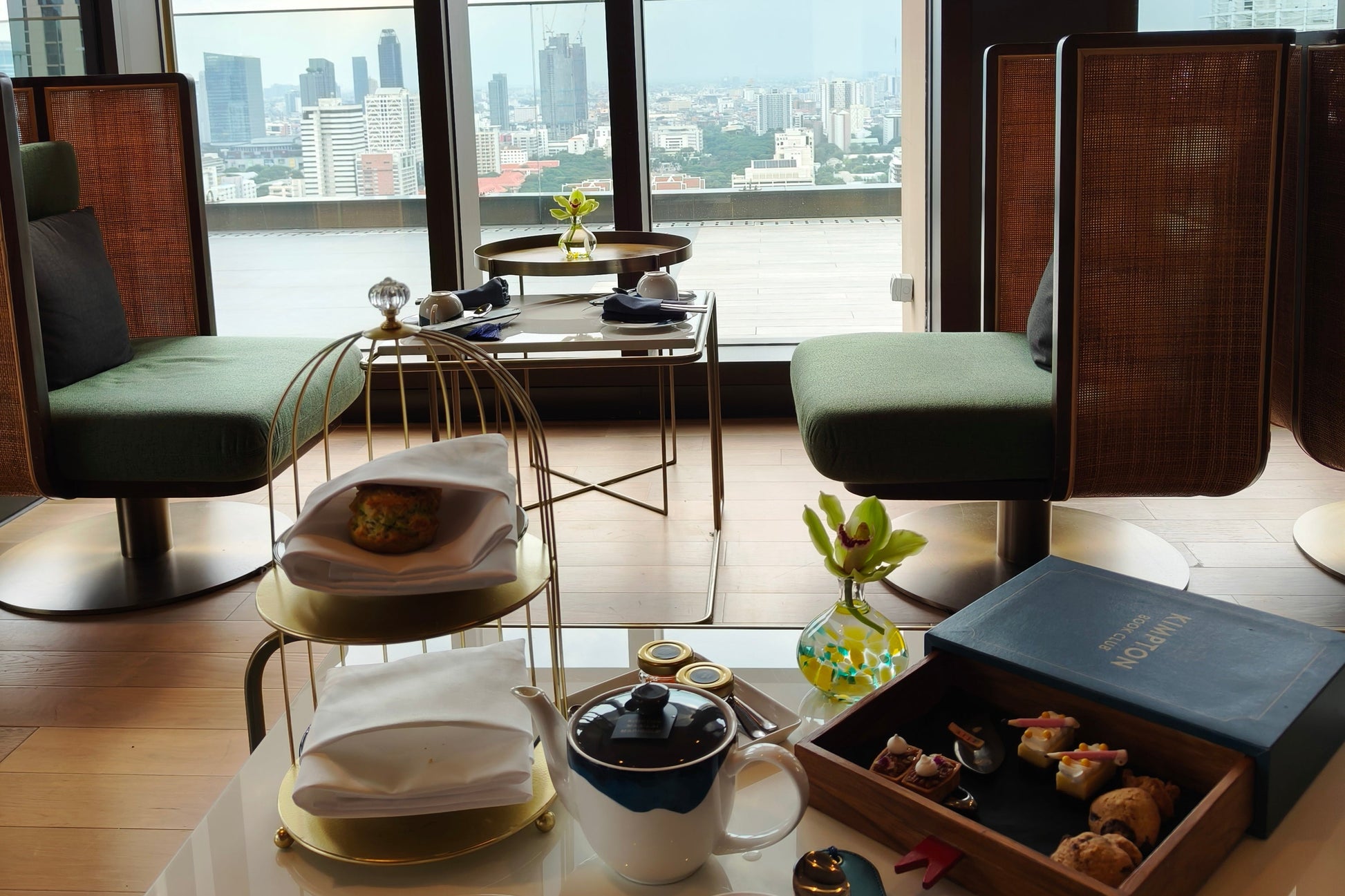 Modern afternoon tea set by window with Bangkok city view at Maa-Lai Library Kimpton hotel