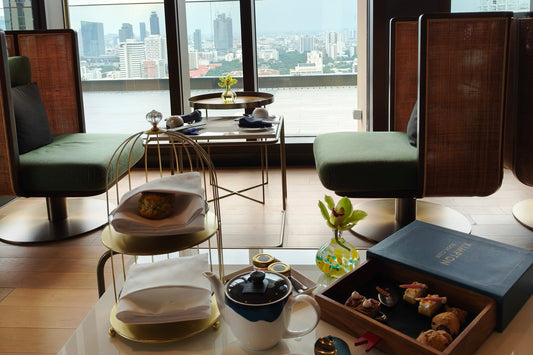 Modern afternoon tea set by window with Bangkok city view at Maa-Lai Library Kimpton hotel
