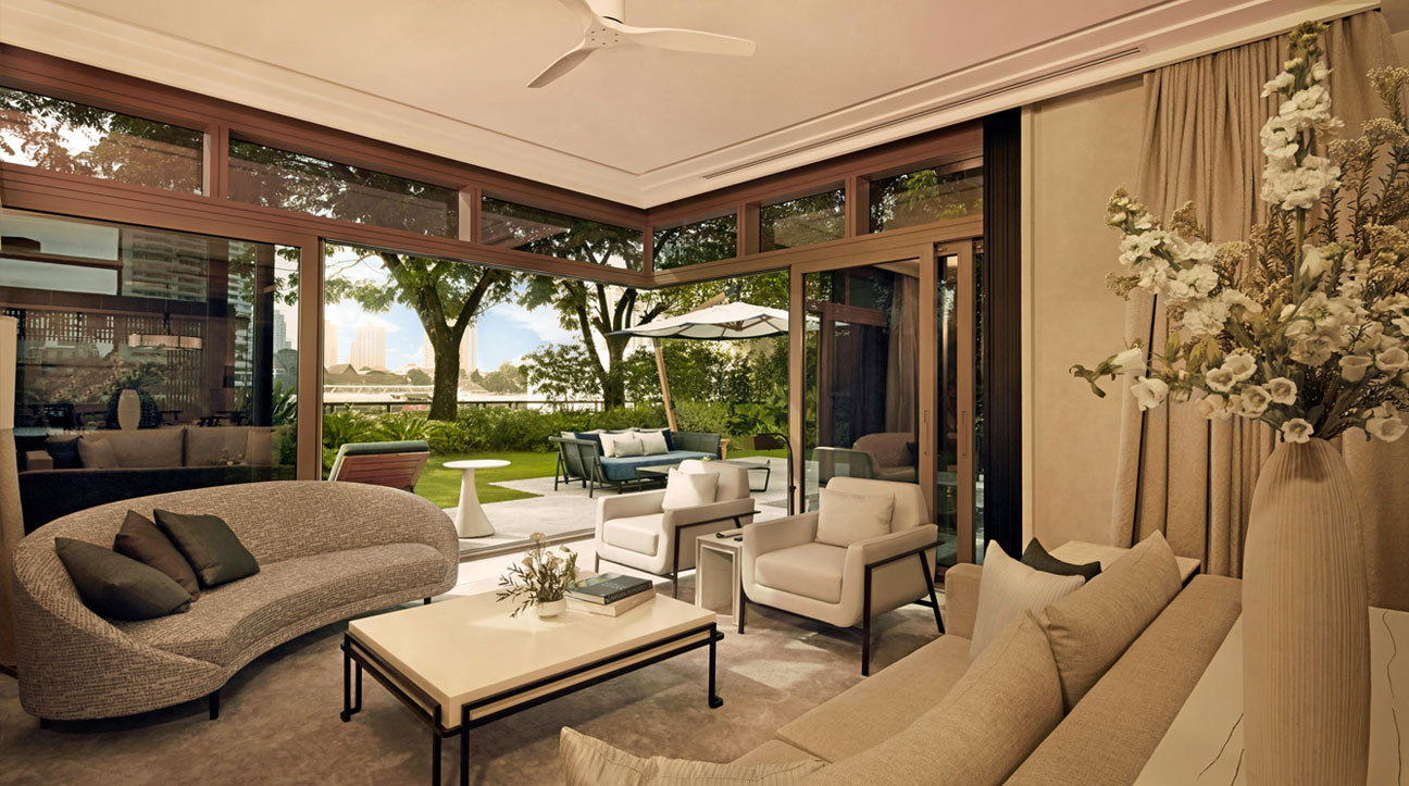 Modernroom with beige sofas, coffee table, and large windows overlooking a garden at Capella bangkok